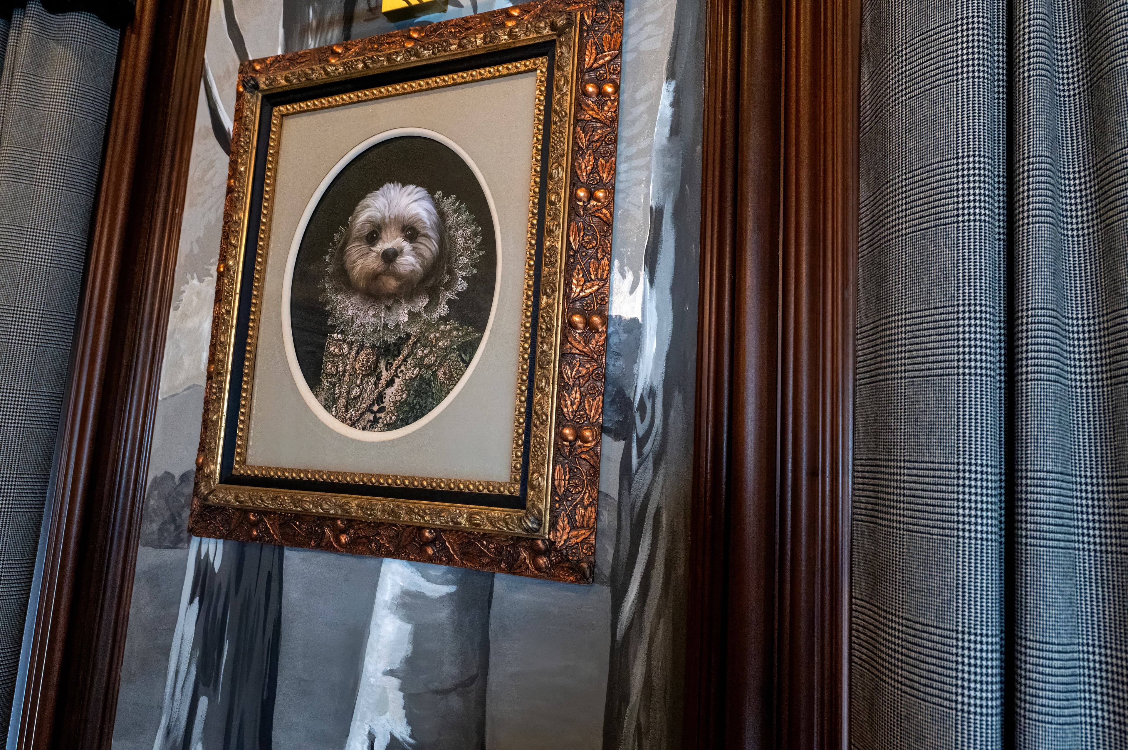 A framed antique portrait painting of a dog on a panelled wall